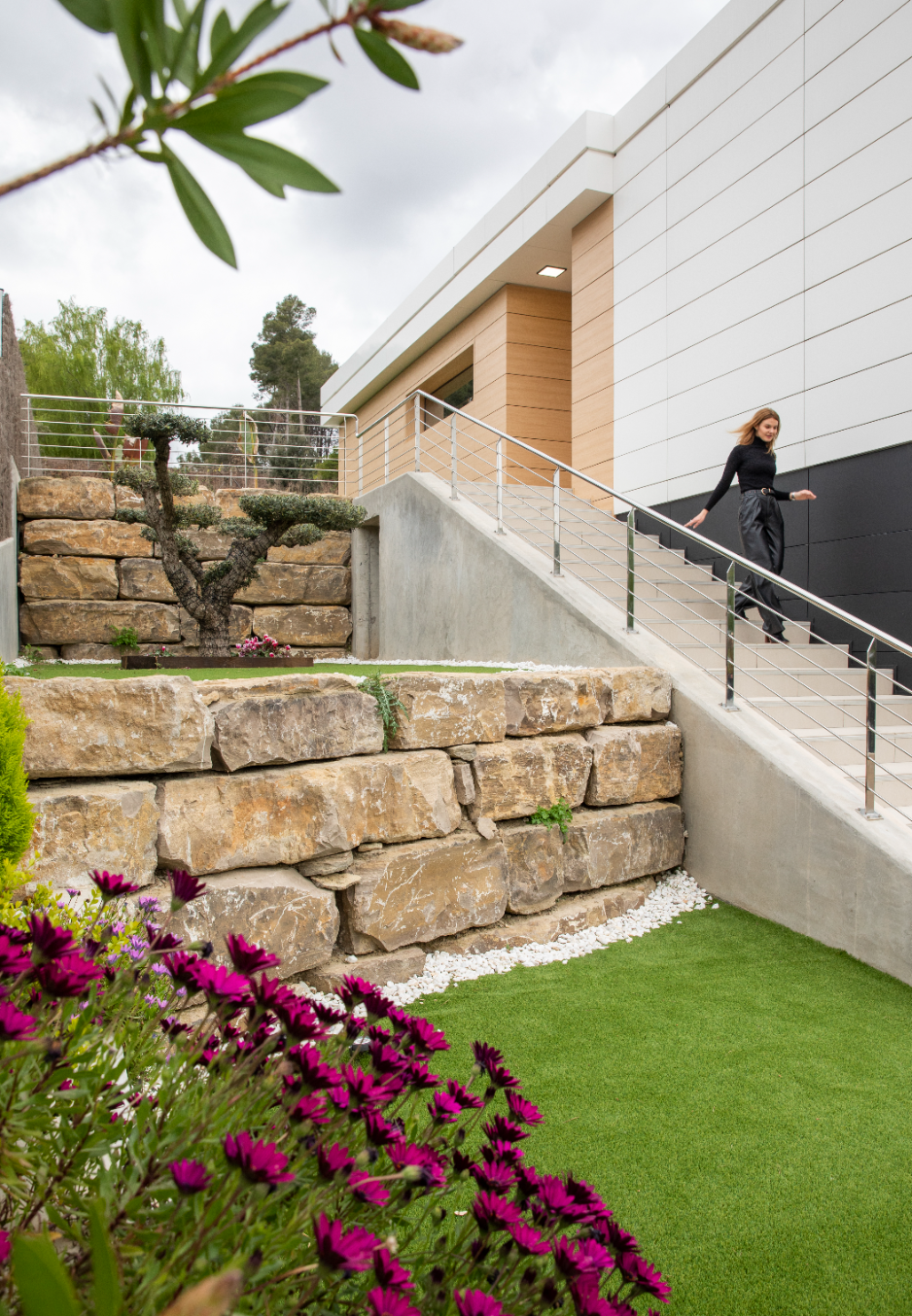 Exterior de casa unifamiliar con muro de piedra y jardín