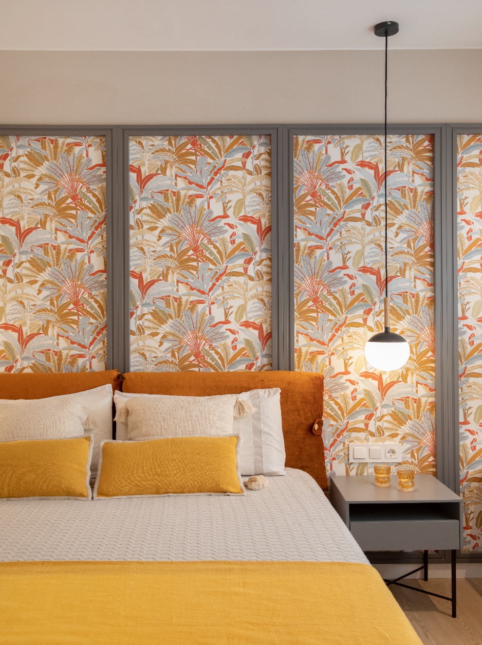 Dormitorio con papel pintado floral y ropa de cama mostaza