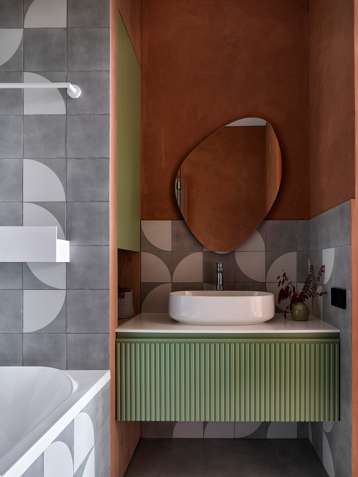 Baño con mueble verde acanalado y espejo orgánico