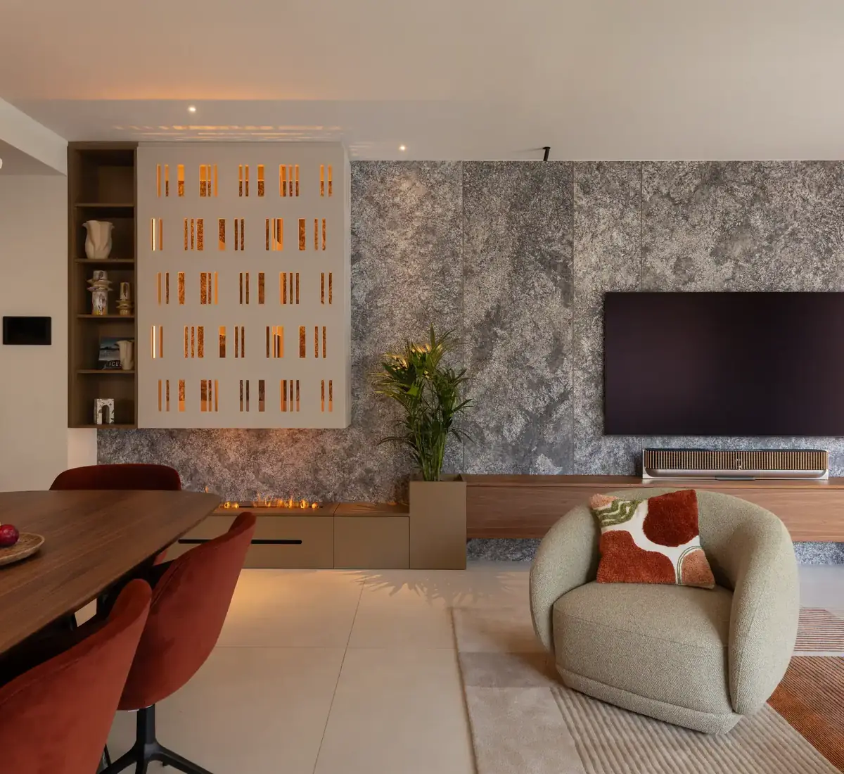 Salón con celosía iluminada y pared de piedra en una vivienda reformada en Sarrià, Barcelona