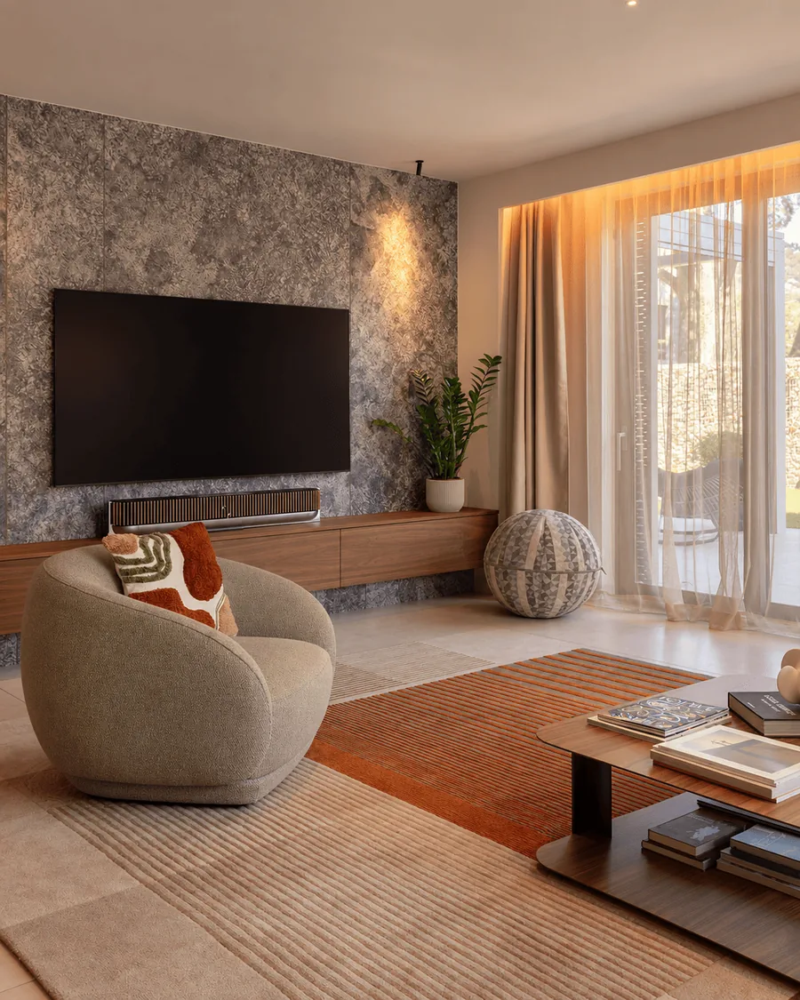 Salón con butaca curva y pared de piedra en una vivienda reformada en Sarrià, Barcelona