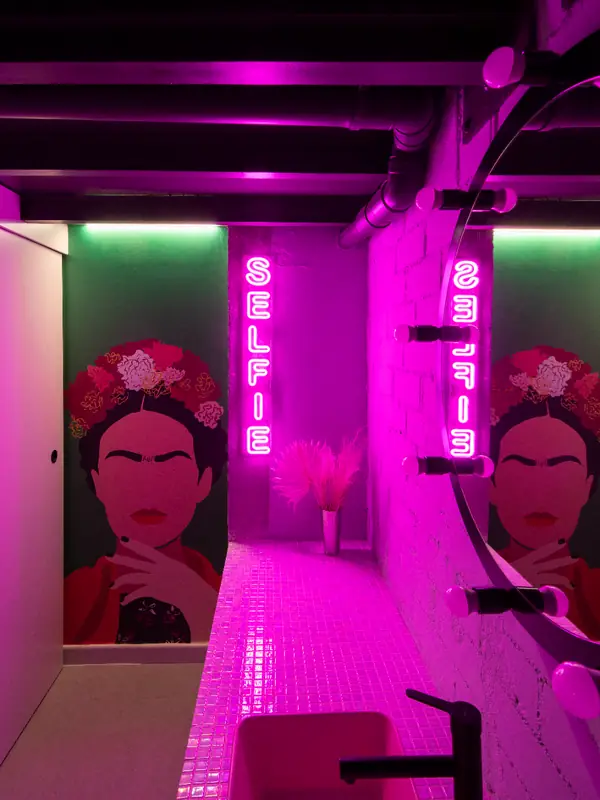 Pasillo con neón rosa y retratos pintados en The Beauty Place