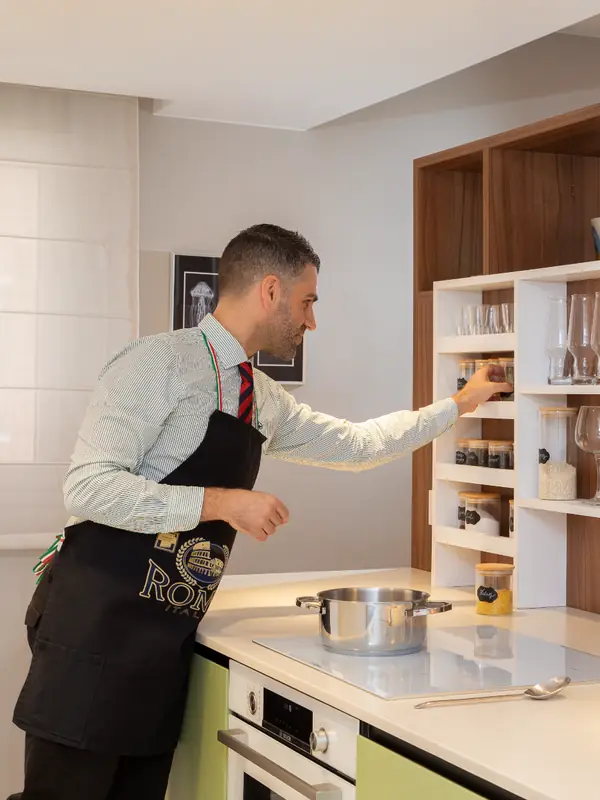 Cocinero en la isla de la cocina del piso tetris, con estantería de nogal a medida