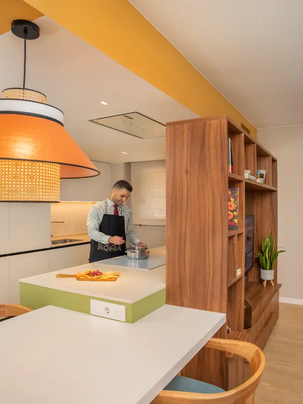 Cocina abierta con isla verde y lámpara de ratán en el piso tetris, Barcelona