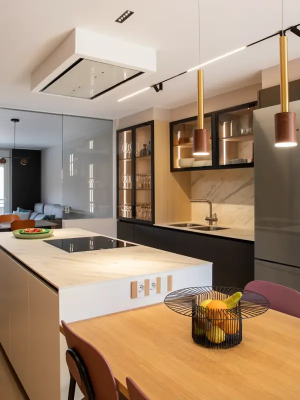 Isla de cocina con encimera de porcelánico y lámparas doradas en la Casa Olesa