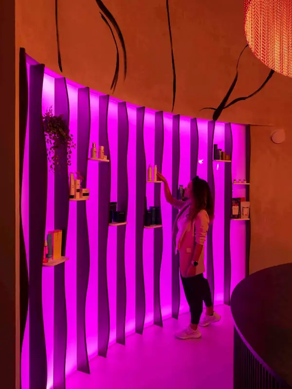 Pared curva con nichos iluminados en magenta en el estudio Cocoon'ink