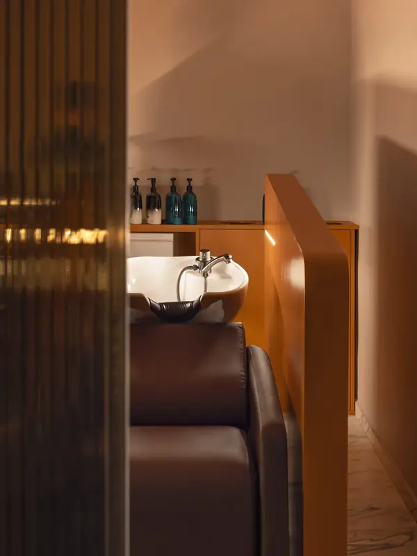 Lavacabezas con madera cálida y luz tenue en Hair Cut Day Gràcia, Barcelona