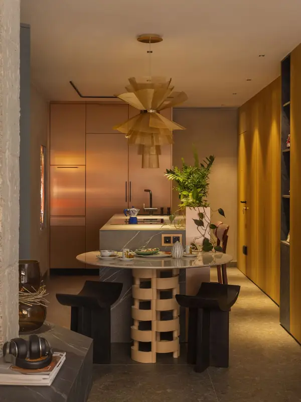 Comedor con lámpara dorada y taburetes de madera en el showroom