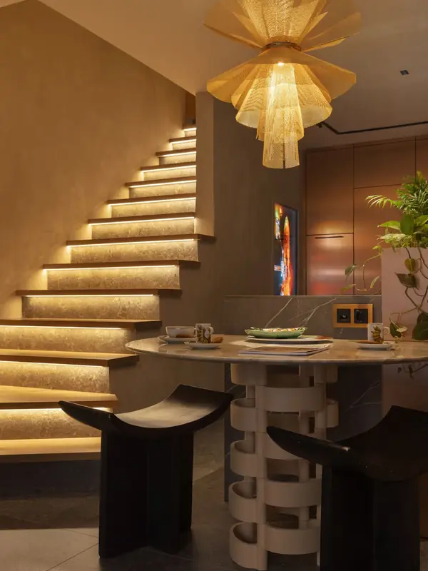 Escalera con peldaños iluminados y mesa con pie artesanal en el showroom