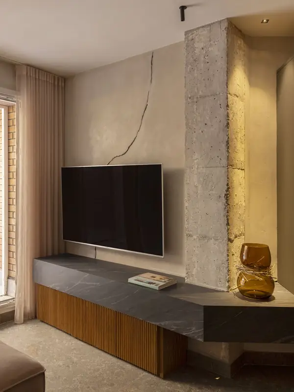 Mueble de televisión de piedra y madera junto a una columna de hormigón en el showroom