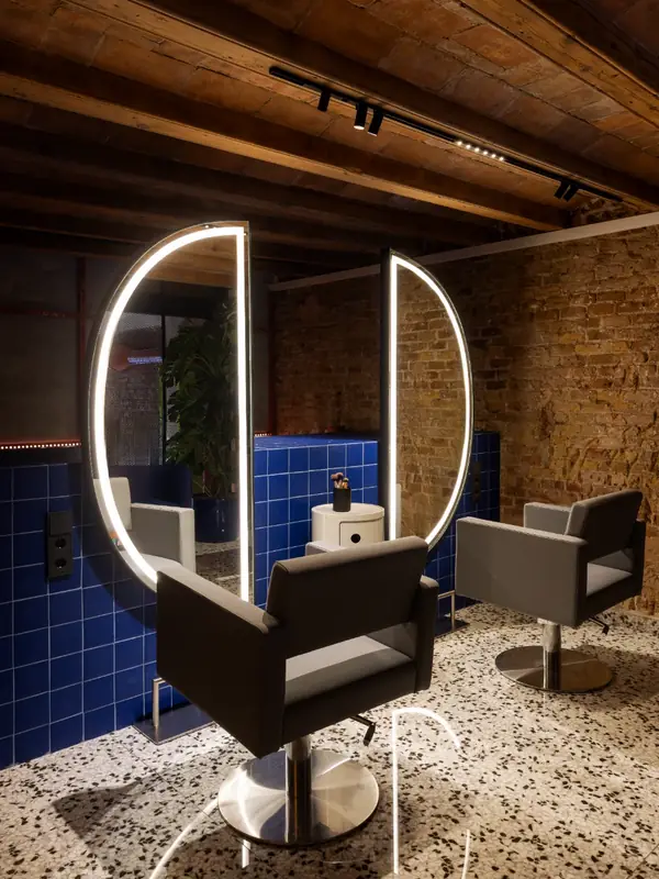 Puesto de peluquería con espejo iluminado y azulejo azul en Hair Cut Day Letamendi