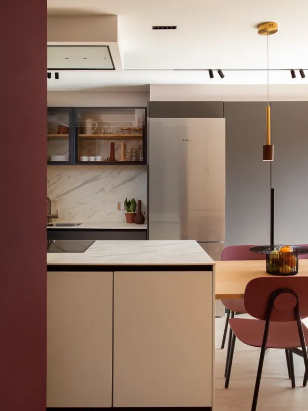 Cocina con isla y comedor junto a una pared granate en la Casa Olesa