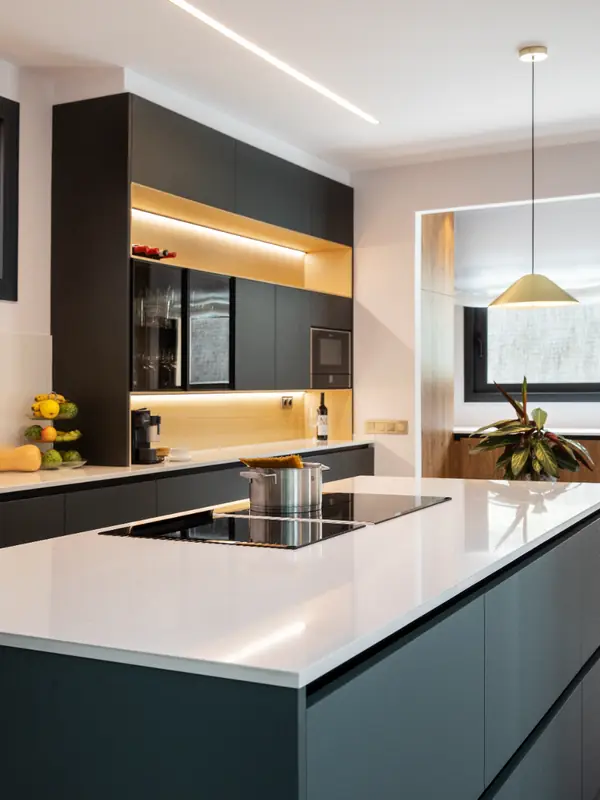 Cocina con isla blanca, armarios oscuros y luz integrada