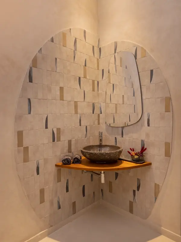 Lavabo de esquina con azulejo artesanal y espejo de forma orgánica