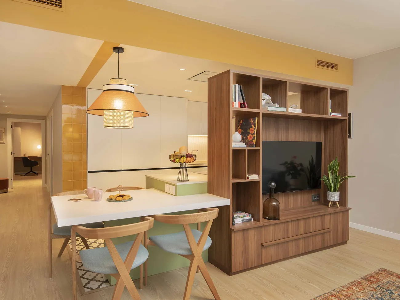 Mueble a medida de nogal con librería y televisión, separando cocina y salón en el piso tetris, Barcelona